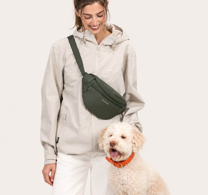 Frau trägt die Eli Dog Bag als Crossbody, daneben ihr Hund