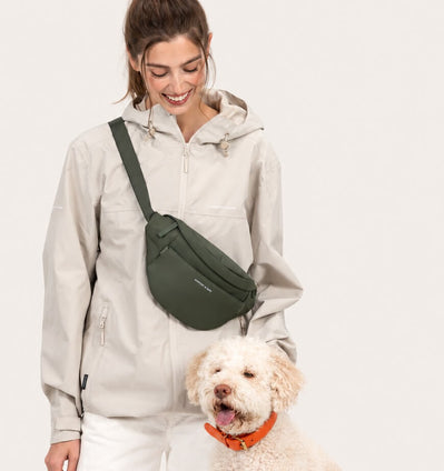 Frau trägt die Eli Dog Bag als Crossbody, daneben ihr Hund